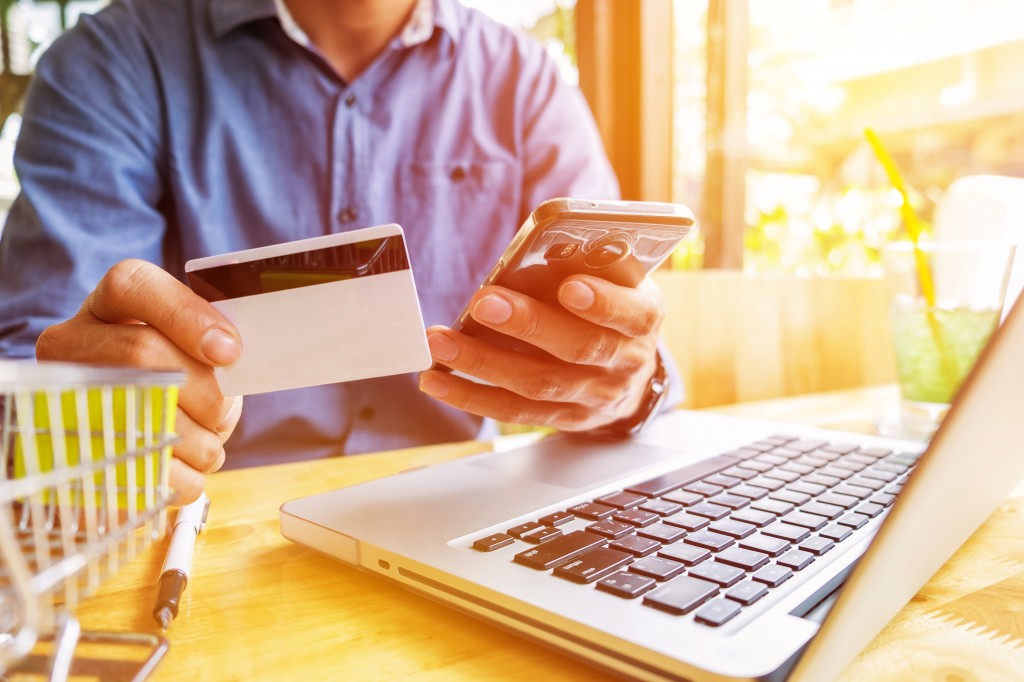 Man holding credit card in hand and entering security code using